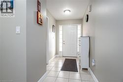 Foyer entrance featuring light tile patterned floors and baseboards - 