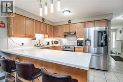 Kitchen with appliances with stainless steel finishes, decorative light fixtures, a breakfast bar area, a peninsula, and backsplash - 