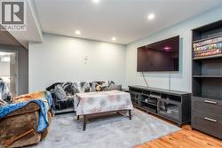 Living room with light wood-style flooring and recessed lighting - 