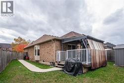 Back of house with brick siding, a fenced backyard, a wooden deck, and roof with shingles - 