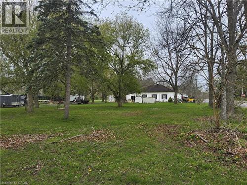 Expansive green lawn with mature trees and a single-story residence featuring a dark roof and white siding - 740 Hillcrest Road, Simcoe, ON - Outdoor