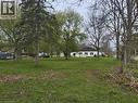 Expansive green lawn with mature trees and a single-story residence featuring a dark roof and white siding - 740 Hillcrest Road, Simcoe, ON  - Outdoor 