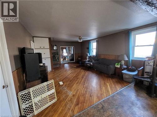 Living room with wainscoting, wood walls, a textured ceiling, wood-type flooring, and a ceiling fan - 740 Hillcrest Road, Simcoe, ON - Indoor