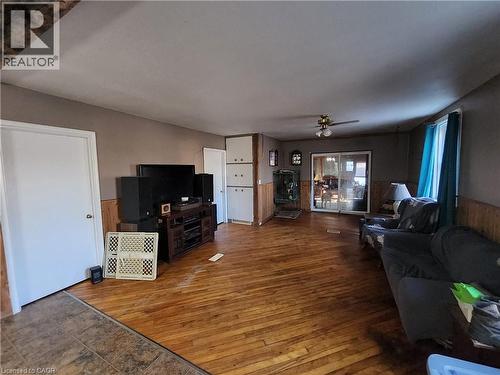Living room featuring a wainscoted wall, hardwood / wood-style floors, wood walls, and ceiling fan - 740 Hillcrest Road, Simcoe, ON - Indoor Photo Showing Living Room