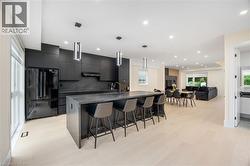 Kitchen with modern cabinets, freestanding refrigerator, a breakfast bar, a large island with sink, and open floor plan - 