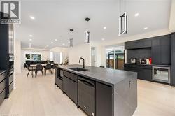 Kitchen featuring dark cabinetry, a large island, modern cabinets, pendant lighting, and recessed lighting - 