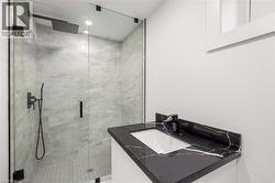 Bathroom with vanity, a marble finish shower, and recessed lighting - 