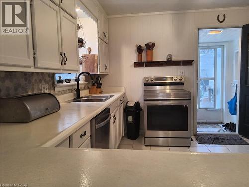 Kitchen featuring stainless steel electric stove, light countertops, light tile patterned floors, dishwasher, and ornamental molding - 509 Queensway W, Simcoe, ON - Indoor Photo Showing Kitchen With Double Sink