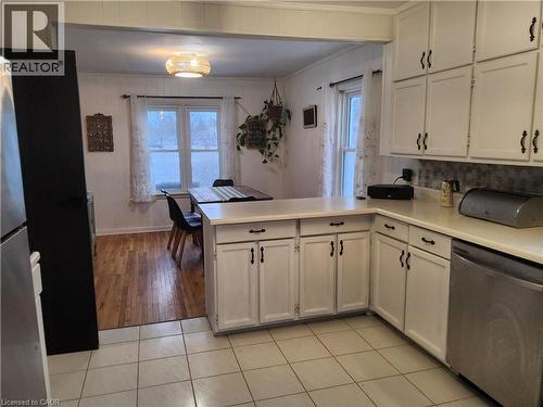 Kitchen with appliances with stainless steel finishes, a peninsula, light countertops, ornamental molding, and plenty of natural light - 509 Queensway W, Simcoe, ON - Indoor Photo Showing Kitchen