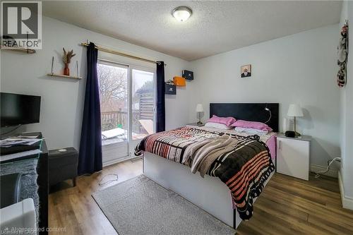 Bedroom featuring access to exterior, a textured ceiling, and wood finished floors - 758 Stone Church Road E, Hamilton, ON - Indoor Photo Showing Bedroom