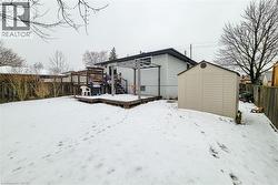 Snow covered rear of property with a storage unit, a wooden deck, and a fenced backyard - 