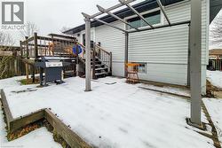 Snow covered patio featuring a patio, stairs, grilling area, and a wooden deck - 