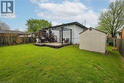 Back of property with a fenced backyard, a storage unit, and a deck - 