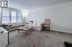 Carpeted living area with a textured ceiling and baseboards - 