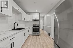 Kitchen featuring appliances with stainless steel finishes, white cabinetry, wainscoting, decorative backsplash, and light wood finished floors - 