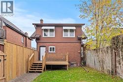 Back of property featuring a fenced backyard, a chimney, and brick siding - 
