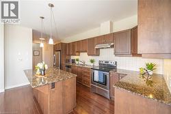 Kitchen with appliances with stainless steel finishes, dark stone counters, decorative backsplash, and pendant lighting - 