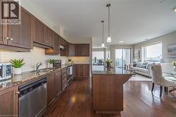 Kitchen with dark stone counters, appliances with stainless steel finishes, decorative light fixtures, a center island, and tasteful backsplash - 