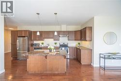 Kitchen featuring hanging light fixtures, appliances with stainless steel finishes, dark stone counters, a kitchen island, and a kitchen bar - 