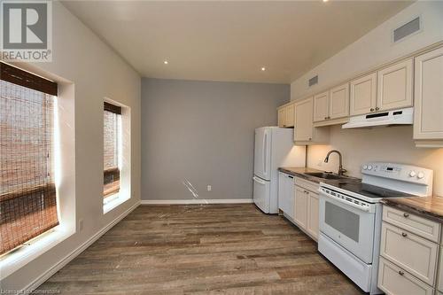 Kitchen featuring white appliances, visible vents, dark wood finished floors, a sink, and under cabinet range hood - 329 King Street E Unit# 3, Hamilton, ON - Indoor Photo Showing Kitchen