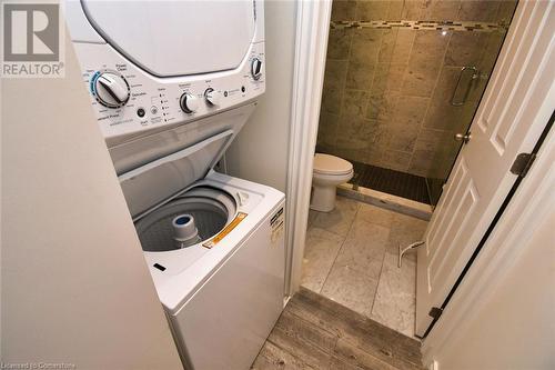 Laundry area with laundry area, wood finished floors, and stacked washer / drying machine - 329 King Street E Unit# 3, Hamilton, ON - Indoor Photo Showing Laundry Room