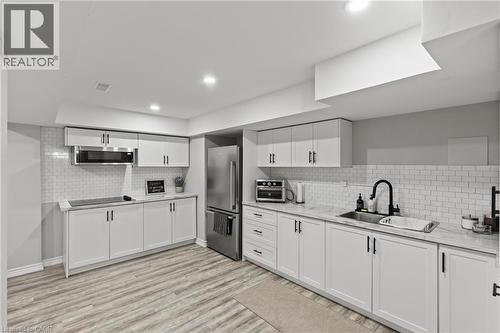 Kitchen with white cabinetry, appliances with stainless steel finishes, light wood finished floors, recessed lighting, and light stone countertops - 62 Esther Crescent Unit# Lower, Thorold, ON - Indoor Photo Showing Kitchen With Upgraded Kitchen