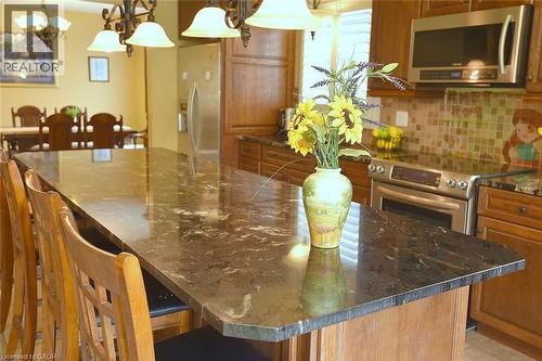 Kitchen with a breakfast bar, dark stone counters, stainless steel appliances, a large island, and hanging light fixtures - 43 Niska Drive, Waterdown, ON - Indoor Photo Showing Dining Room