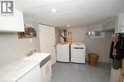 Laundry room featuring finished concrete flooring, washing machine and clothes dryer, cabinet space, and recessed lighting - 
