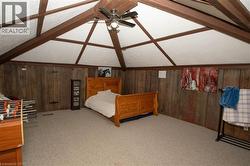 Bedroom featuring wood walls, carpet floors, and ceiling fan - 
