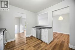 Kitchen featuring white cabinets, appliances with stainless steel finishes, dark countertops, dark wood-style flooring, and decorative light fixtures - 
