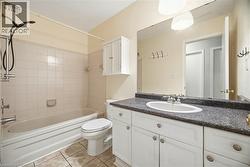Bathroom with washtub / shower combination, vanity, and light tile patterned flooring - 