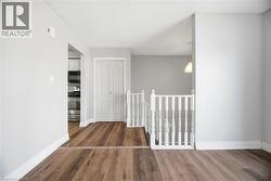 Hallway with an upstairs landing and dark wood-style floors - 