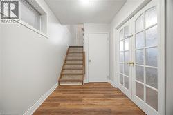 Stairway featuring a textured ceiling, wood finished floors, and french doors - 