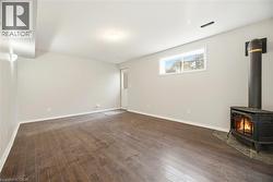 Unfurnished living room featuring a wood stove and dark wood-style flooring - 