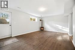 Unfurnished living room with a wood stove and dark wood-type flooring - 