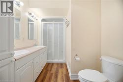 Bathroom featuring double vanity, a shower stall, and light wood-type flooring - 