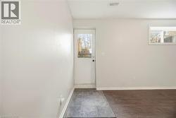 Unfurnished room featuring baseboards and dark wood-style flooring - 