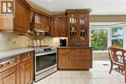 Kitchen featuring stainless steel electric range, light tile patterned flooring, backsplash, custom exhaust hood, custom maple cabinetry - 3 Atkins Drive, Hamilton, ON - Indoor Photo Showing Kitchen