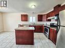 Kitchen with reddish brown cabinets, stainless steel appliances, a textured ceiling, a kitchen island, and under cabinet range hood - 132 Udvari Crescent Unit# 3, Kitchener, ON  - Indoor Photo Showing Kitchen With Double Sink 