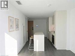 Kitchen featuring modern cabinets, a breakfast bar, white cabinets, and dark wood-type flooring - 