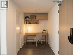 Home office featuring dark wood finished floors, built in desk, and electric panel - 