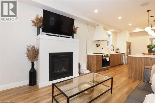 Living room with light wood-style floors, a glass covered fireplace, and recessed lighting - 238 Eagle Street S, Cambridge, ON - Indoor Photo Showing Living Room With Fireplace