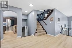 Unfurnished living room with arched walkways, light wood-style floors, stairs, and recessed lighting - 