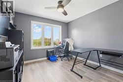 Home office featuring light wood-style flooring, a ceiling fan, and a textured ceiling - 