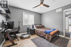 Bedroom with a desk, light wood-style floors, a textured ceiling, and a ceiling fan - 