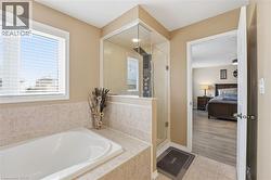 Ensuite bathroom featuring a garden tub, light tile patterned floors, and a shower stall - 