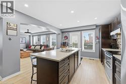 Kitchen with dark brown cabinets, a kitchen bar, arched walkways, stainless steel appliances, and open floor plan - 