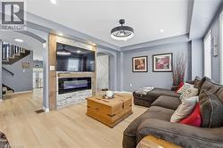 Living room featuring arched walkways, stairway, a glass covered fireplace, and wood finished floors - 
