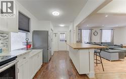 Kitchen featuring open floor plan, a breakfast bar area, appliances with stainless steel finishes, white cabinets, and dark wood-style floors - 