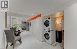 Washroom with stacked washing machine and dryer, light marble finish flooring, and recessed lighting - 
